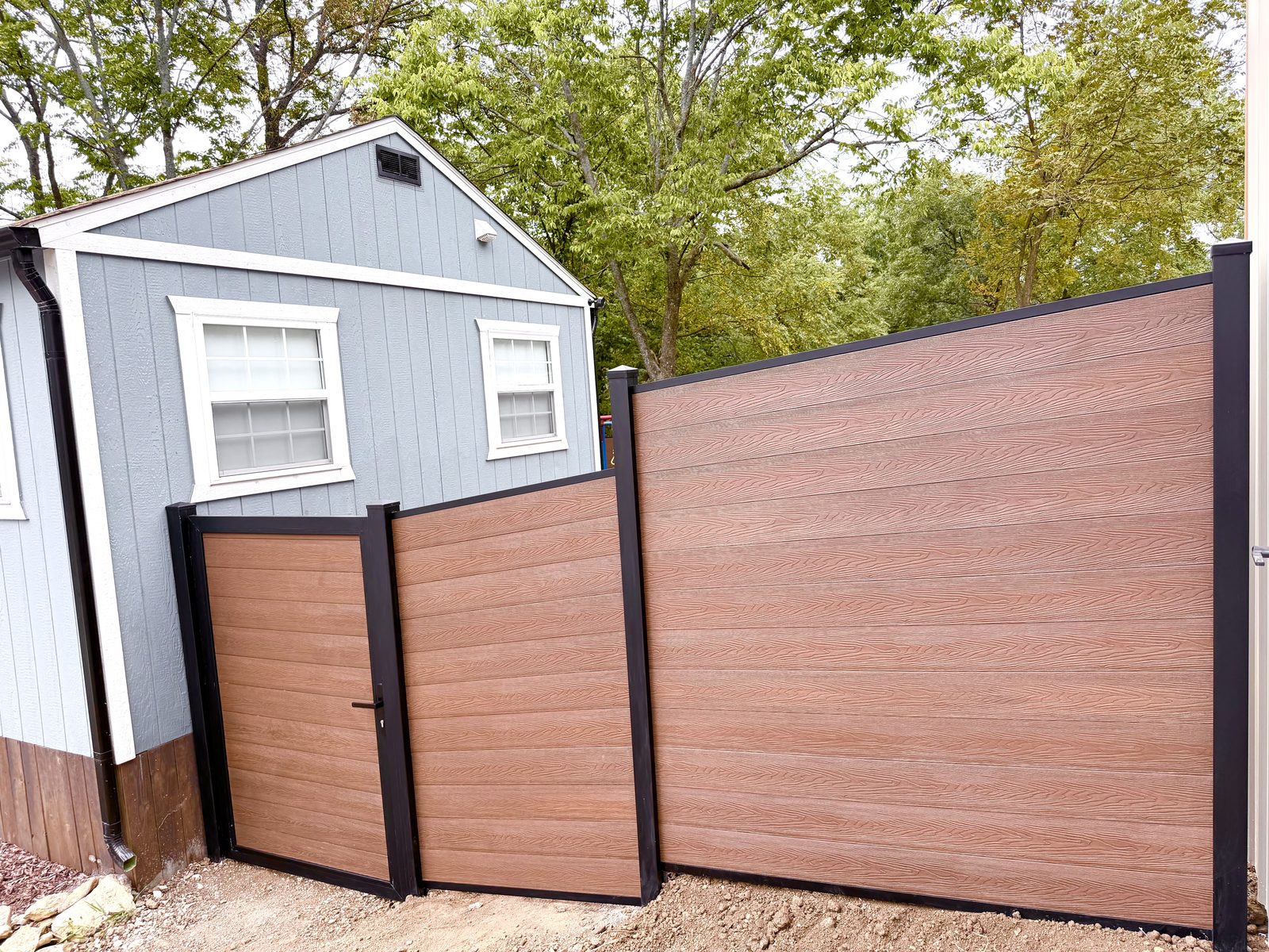 Brown horizontal privacy fence and matching walk gate beside a gray shed.
