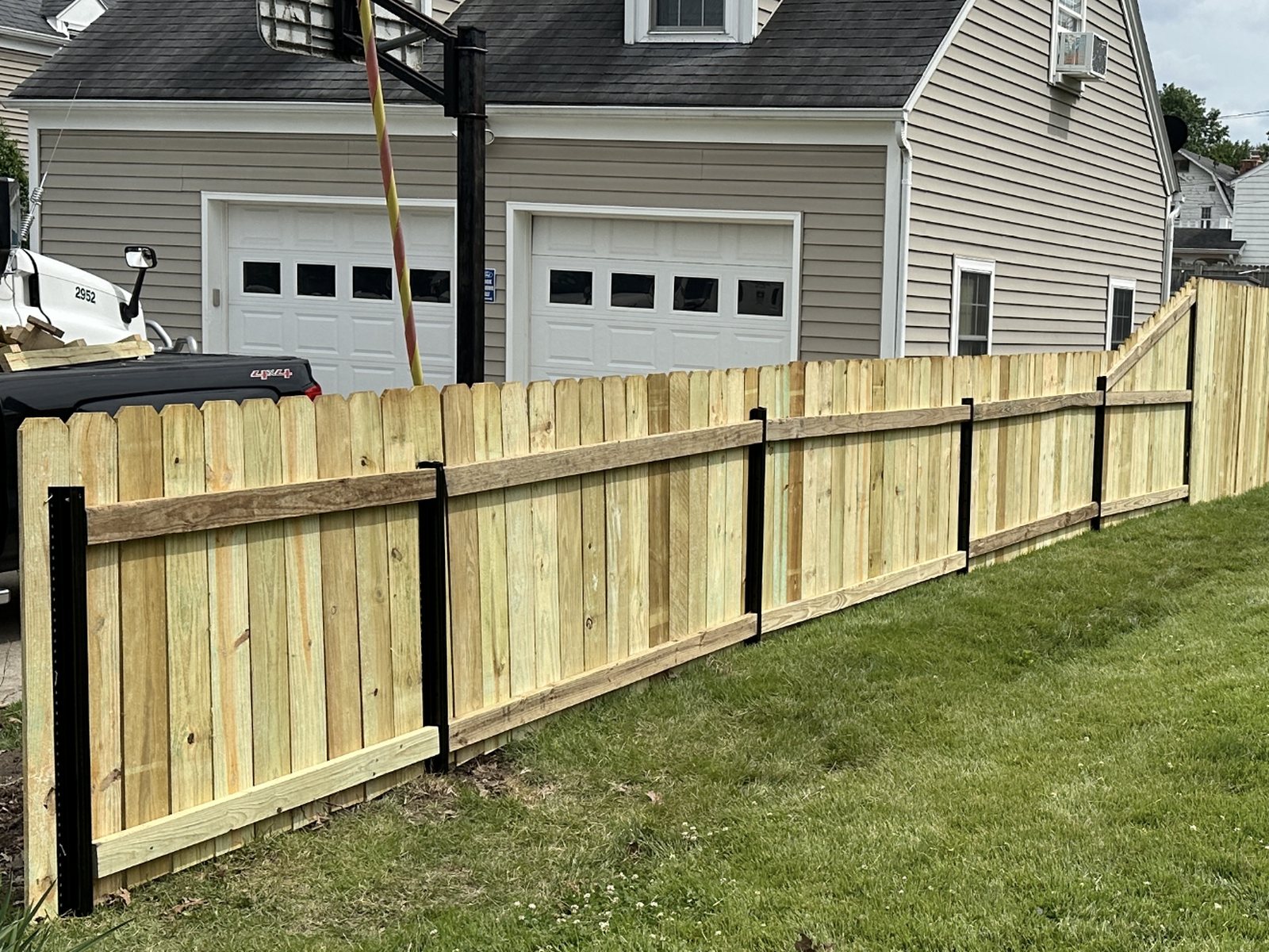 Wood privacy panels on black steel posts running a clean line along a driveway, installed by Get Your Fence On