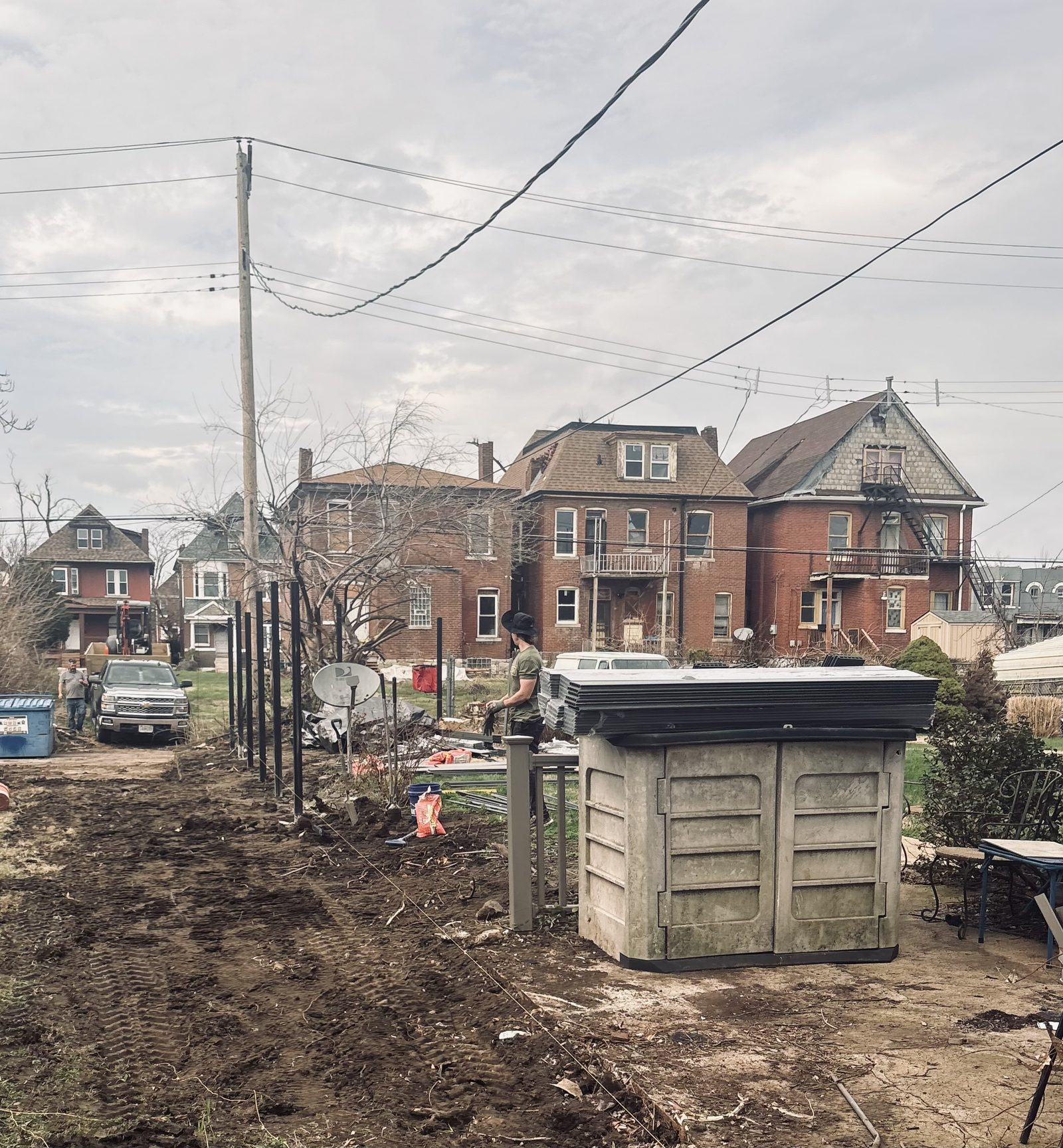 A Get Your Fence On crew member setting line posts with fence panels staged on site, mid-installation