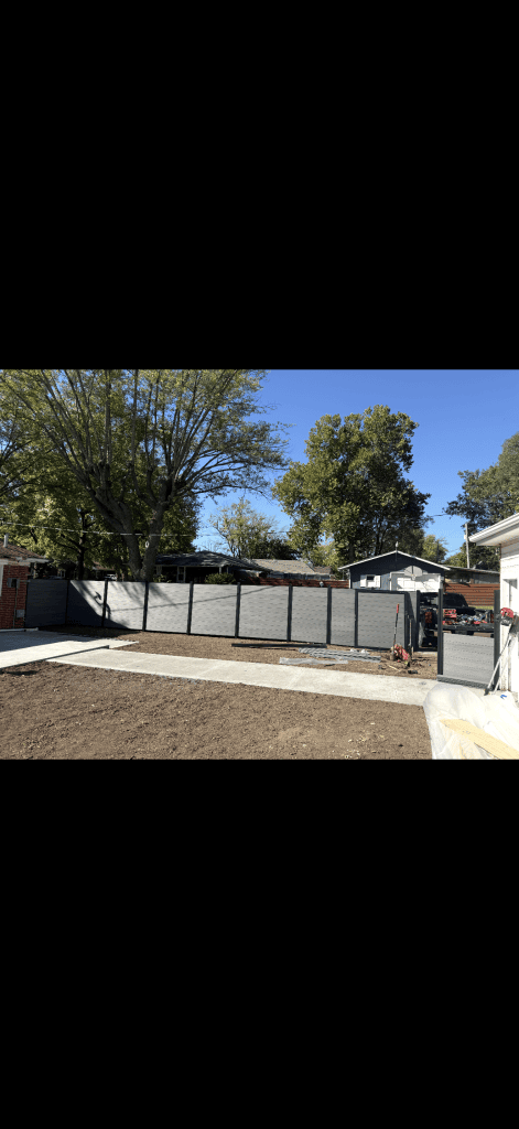 Gray horizontal privacy fence and an open walk gate across a yard with concrete paths.