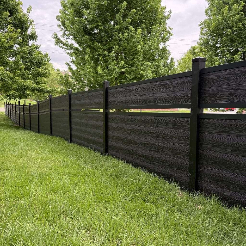 Close view along a dark horizontal fence with a narrow gap near the top beside a green lawn.