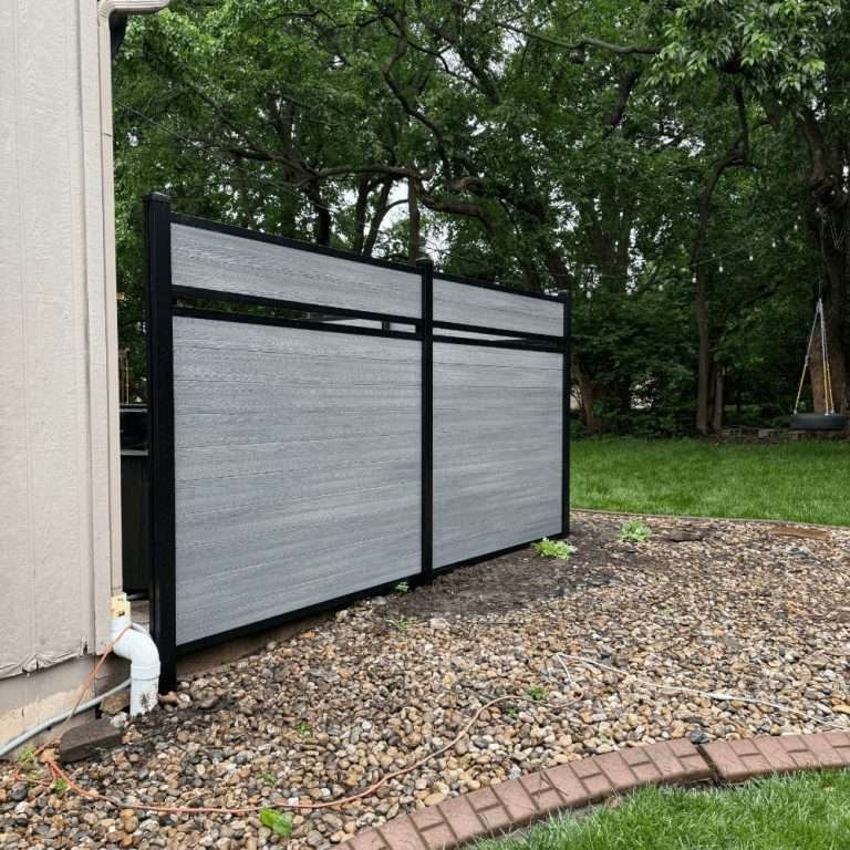 Gray fence panels with a narrow open accent band beside a house and gravel bed.