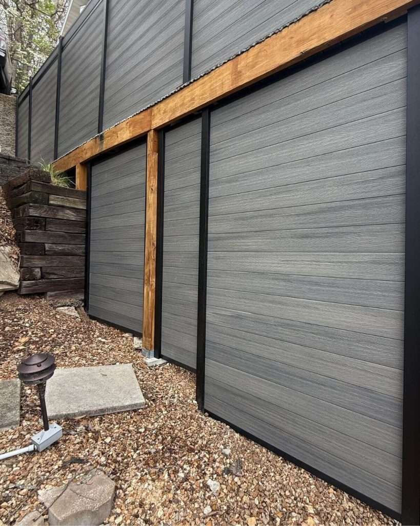 Gray horizontal privacy panels with black framing above and below a timber support beam.
