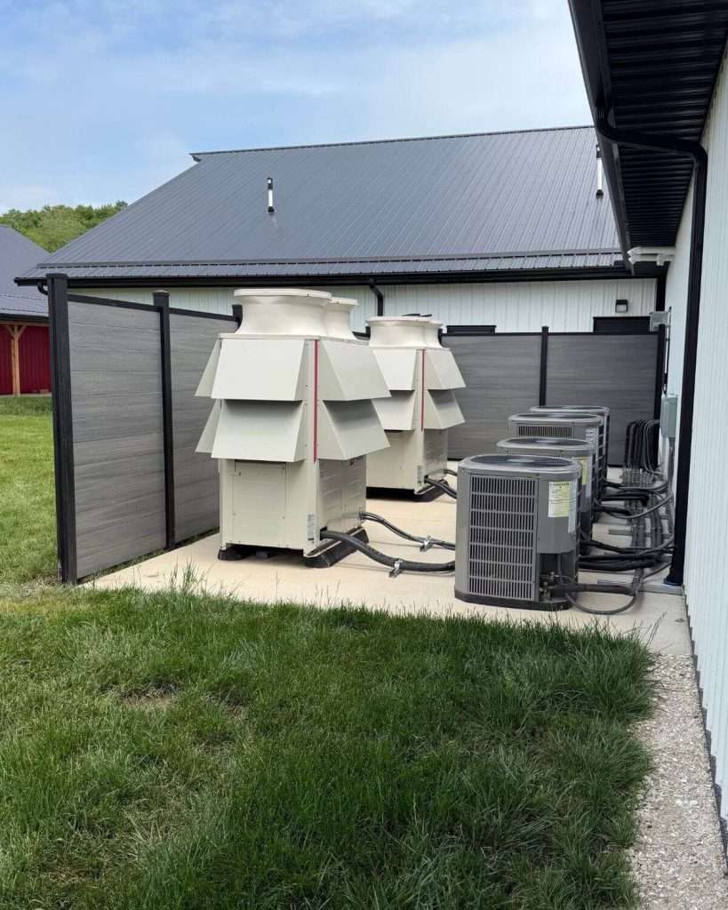 Gray privacy screen around outdoor mechanical equipment beside a building.