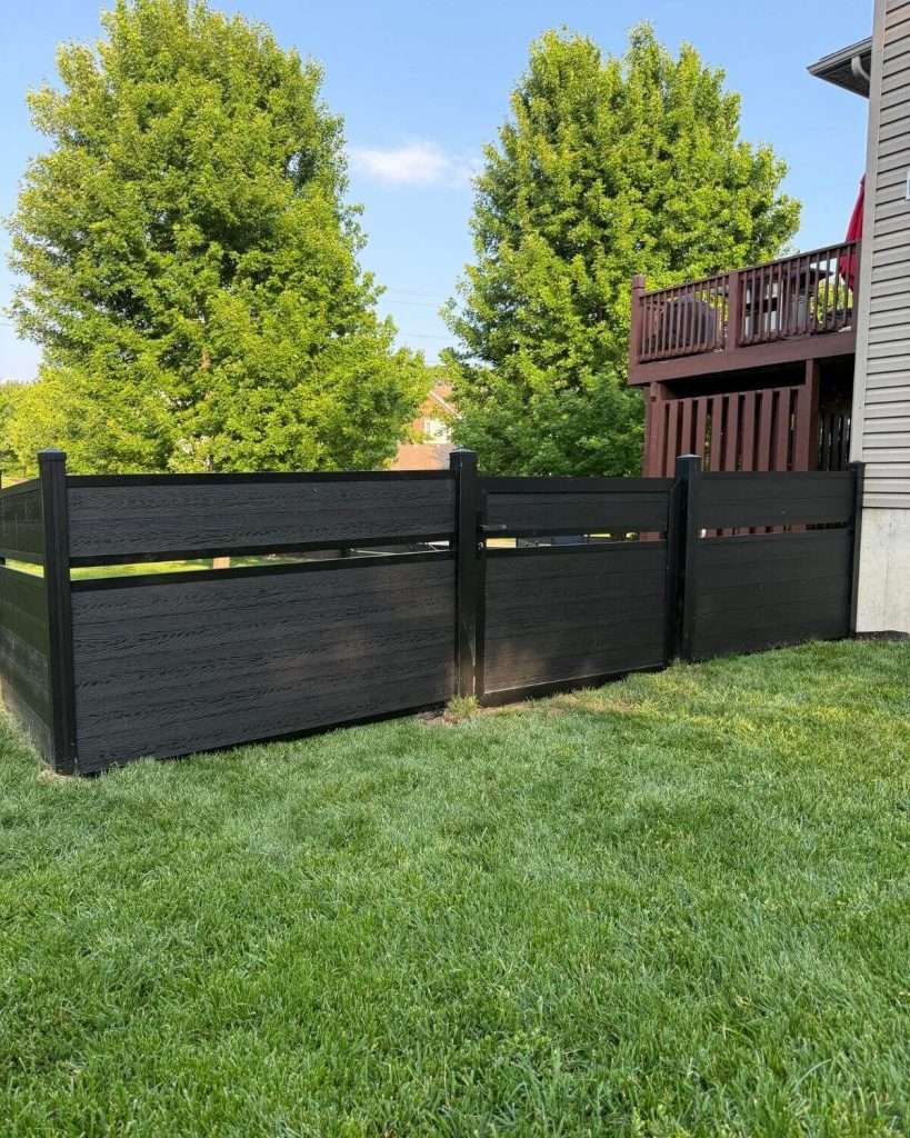 Dark horizontal fence with an open accent band beside a lawn and raised deck.