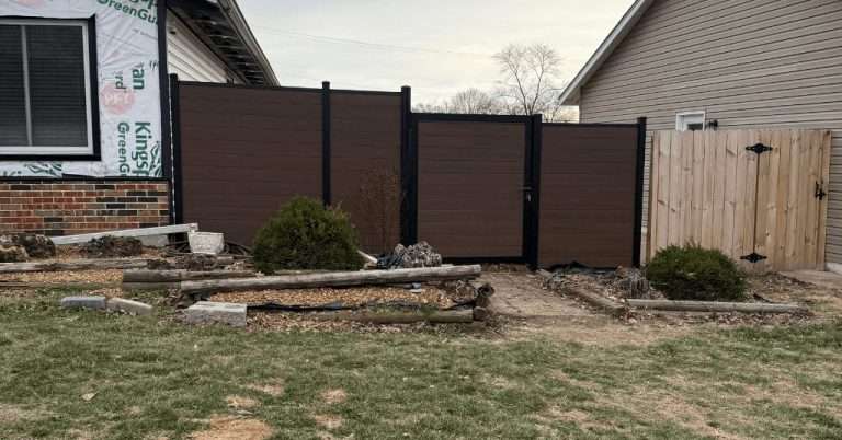 Brown horizontal fence and gate meeting a wood picket gate between houses.