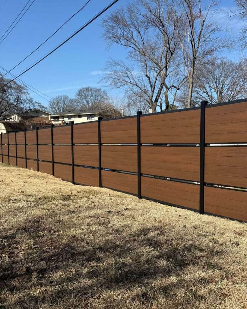 Brown horizontal fence with narrow open bands along a sloping grass boundary.